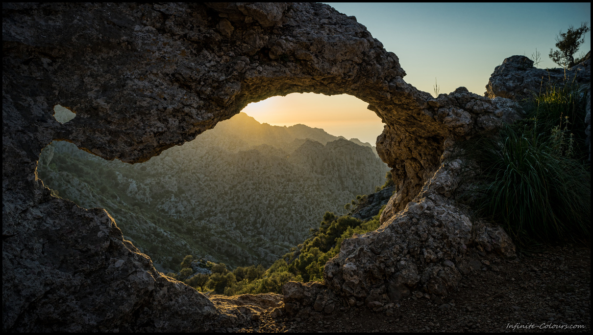 View through the natural arch on the S'Entreforc karst mountains, Torrent de Pareis at sunset