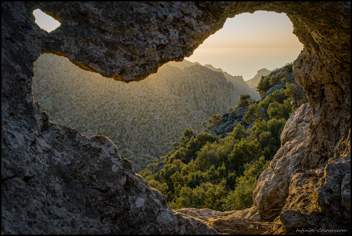 View through the natural arch on the S'Entreforc karst mountains, Torrent de Pareis at sunset